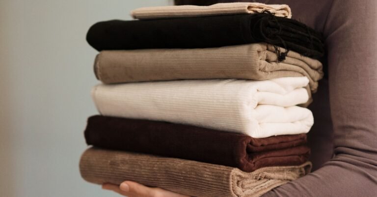 Pilha de tecidos bombazine / corduroy em diferentes cores, com textura canelada em relevo, utilizados em vestuário, decoração e têxteis-lar.
