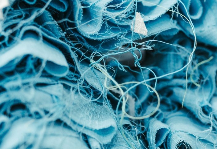 Retalhos e fios de tecidos azuis utilizados como matéria-prima têxtil reciclada.