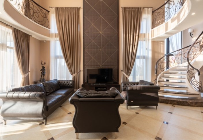 Sala elegante com cortinados altos e sofás estofados em tons neutros.